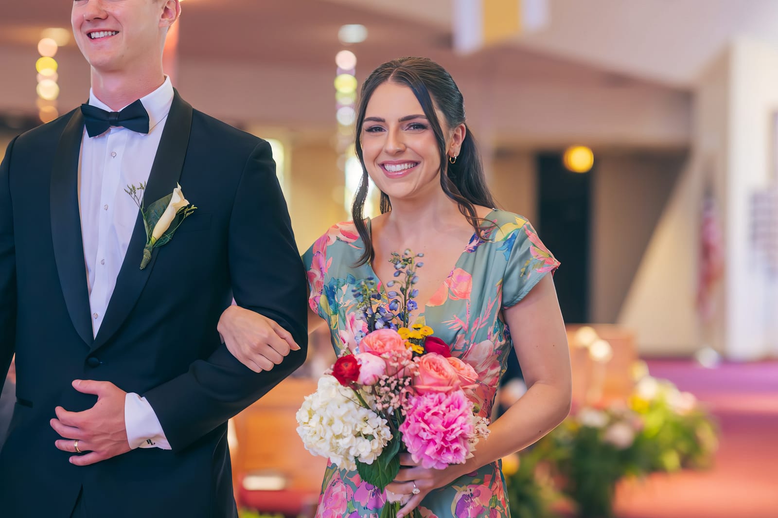 A bridesmaid walking down the aisle on a groomsman's arm